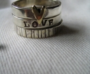 Stack of three rings with heart and etched designs.