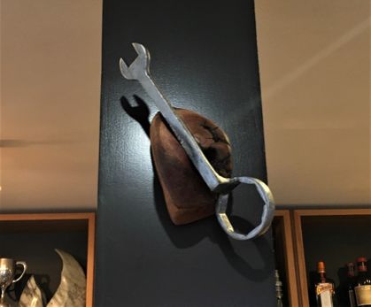 An antique heavy vehicle ring spanner matched with cherry wood, original wall art.